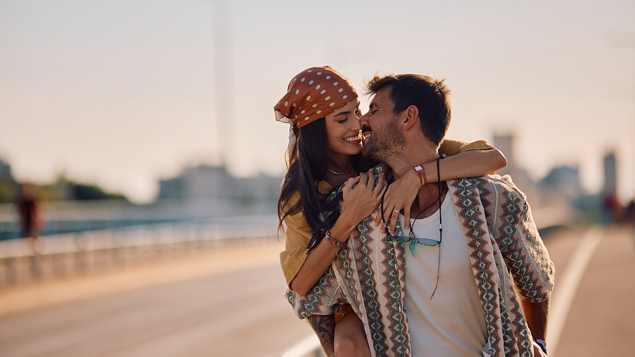 Couple embracing on a bridge with a cityscape in the background